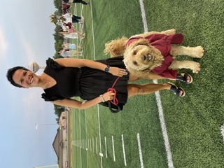 Jill on the Forest Lake athletic field with her dog in a maroon Rangers jersey